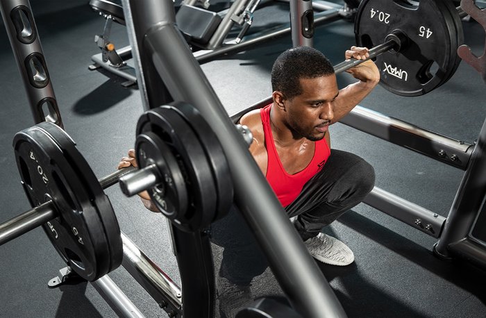 Male athlete performing a squat in the rack. 